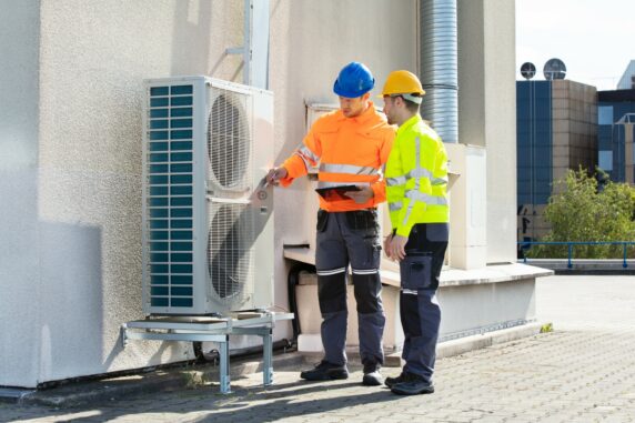 Two technicians checking air conditioning unit