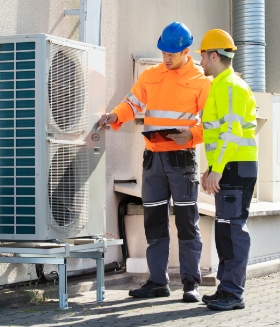Two technicians checking air conditioning unit