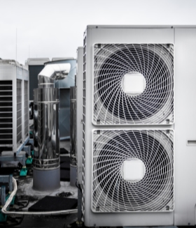 Commercial air conditioning units on the roof with round fan grills and other units and parts of ventilation system.